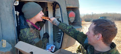 Breakfast of Champions – Cpl Zach Crouse holds Cpl Emily Solberg-Wells’ pizza for her during TAPV repairs.