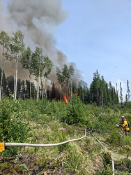 MCpl Shemenauer directs soldiers in building a hose guard in front of advancing flames. Once established, the guard was successful in holding the fire until heavy equipment was able to move in to build a dozer guard, effectively halting the fire’s advance.